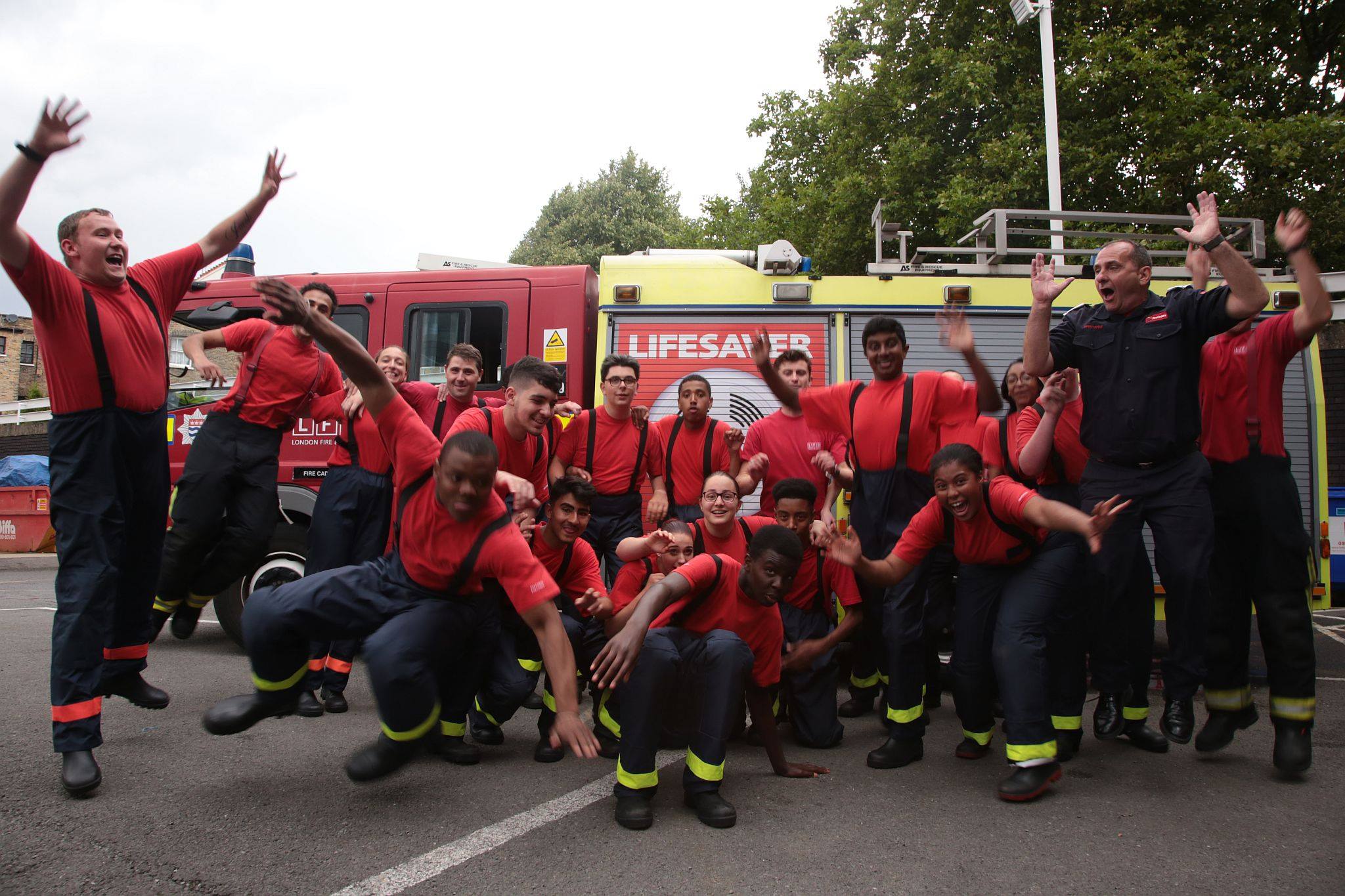 Fire Cadets jumping and waving their arms in front of a fire engine 