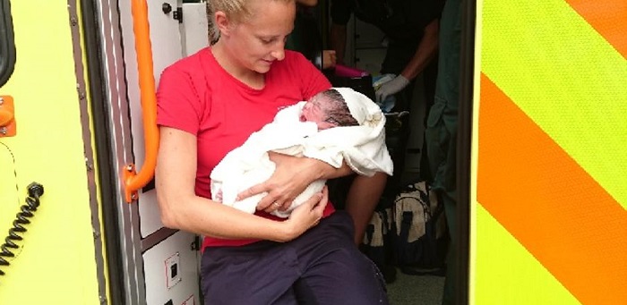 Firefighter holding a brand new born baby 