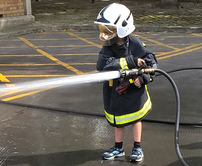 Thomas with a helmet on whilst holding a hose 