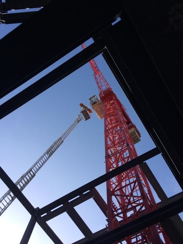 Looking from underneath at a red crane that reaches high into the sky 