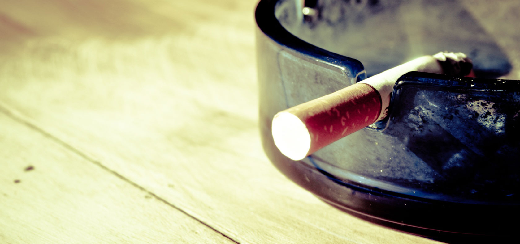 Cigarette stub resting on a glass ash tray 