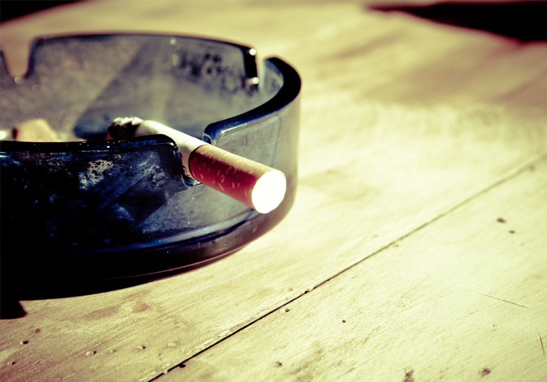 Cigarette stub resting on a glass ash tray 