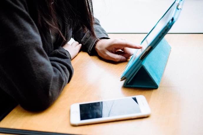 Woman scrolling through a tablet with a blue cover 