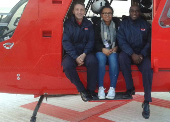 Two smiling firefighters sat with a young woman they rescued 