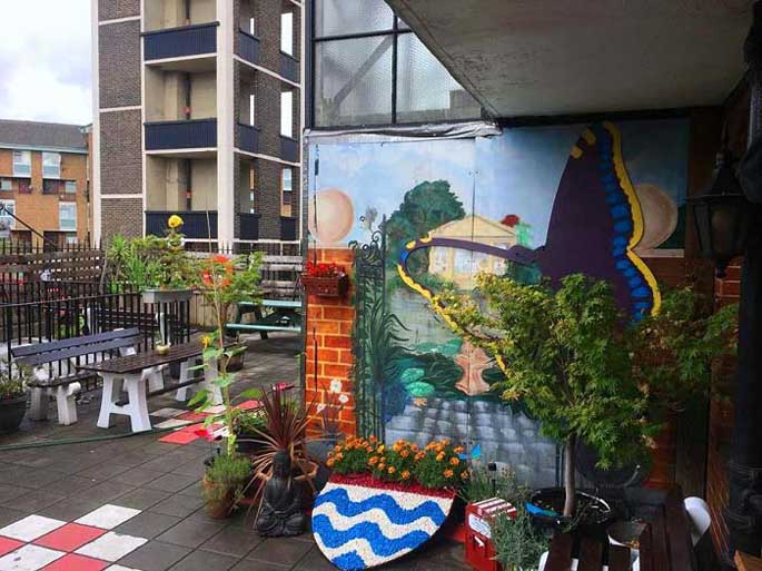 The Brixton mindfulness garden with plants and flowers and a colourful mural on one wall 