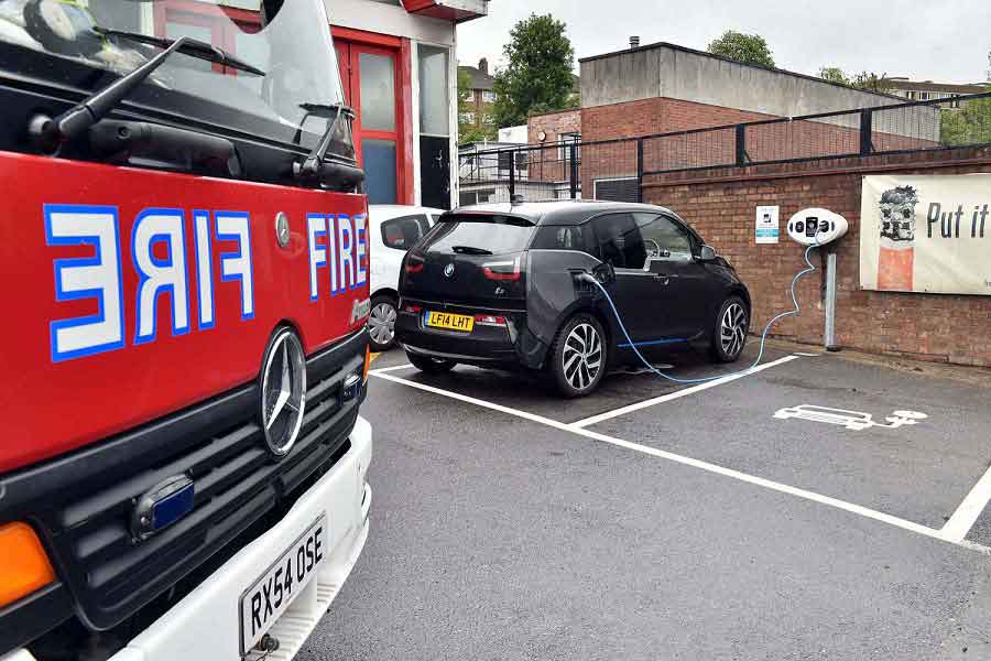 A car using the charge point with the front a fire engine in the foreground