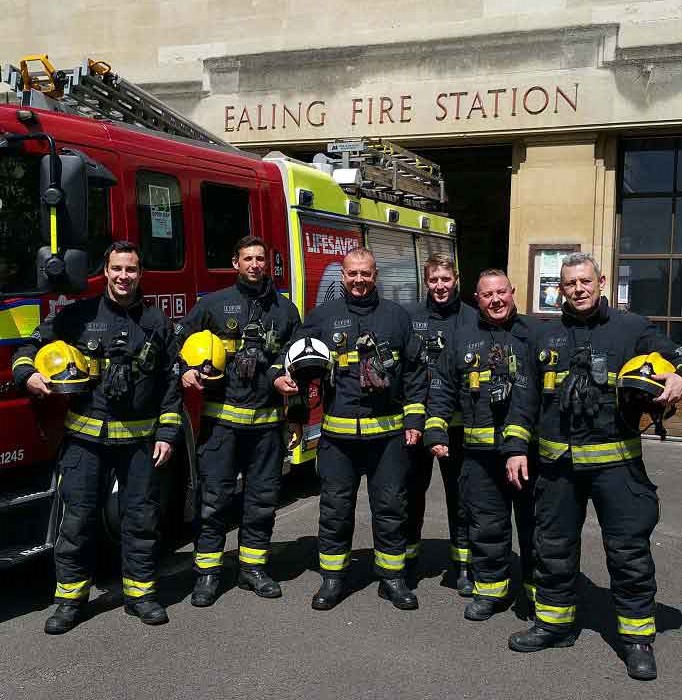 Firefighters standing in front of fire engine in uniform