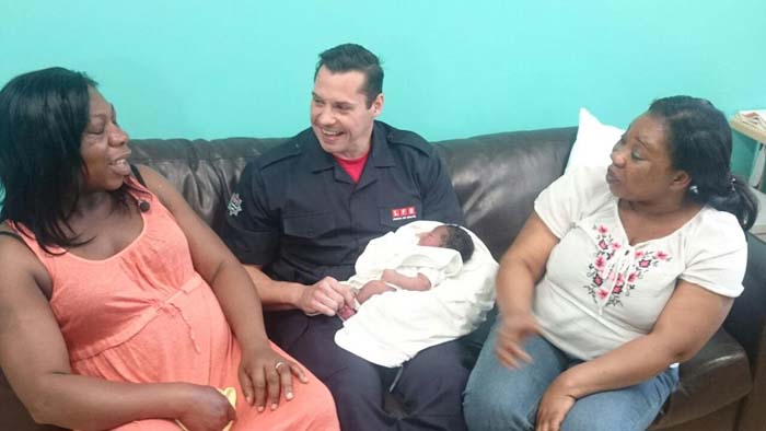 Firefighter James Stennett sitting between the mother of the baby he delivered and the babies aunt