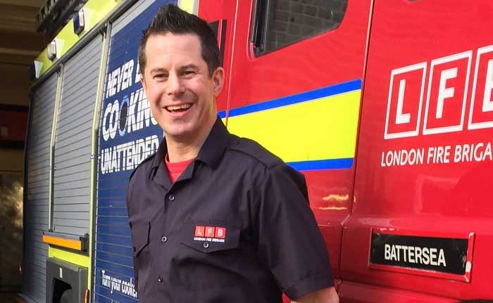 Stuart McDonald stood in front of a fire engine smiling 