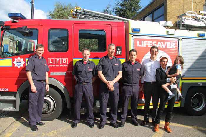 Poppy and her mum with four firefighters in the sunshine next to a fire engine 