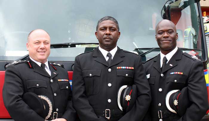 3 Firefighters standing in front of red fire engine