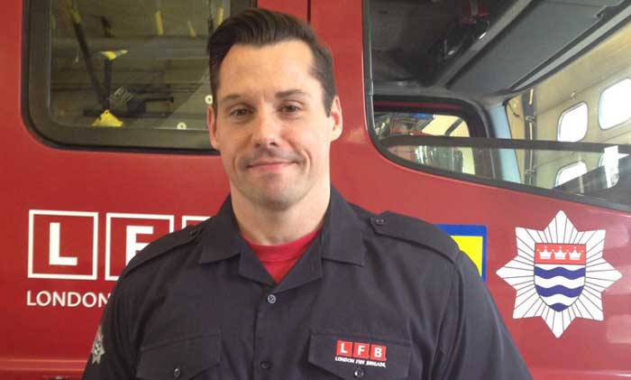 Firefighter James Stennett smiling in front of a fire engine 