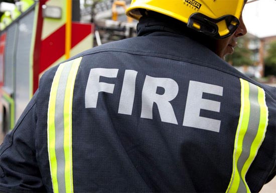 Firefighter in PPE with his back to the camera and fire written across the back 