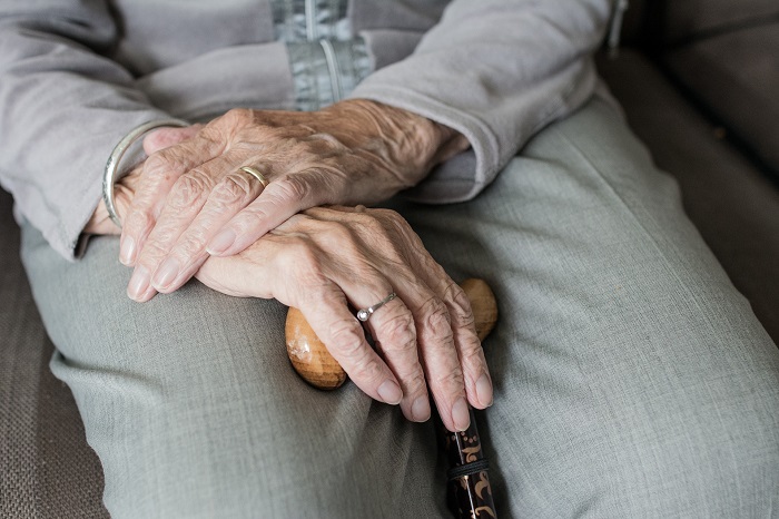 Older person's hands holding a walking stick