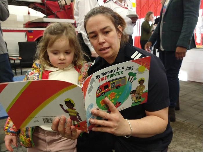 Firefighter reading 'My Mummy is a firefighter' to child