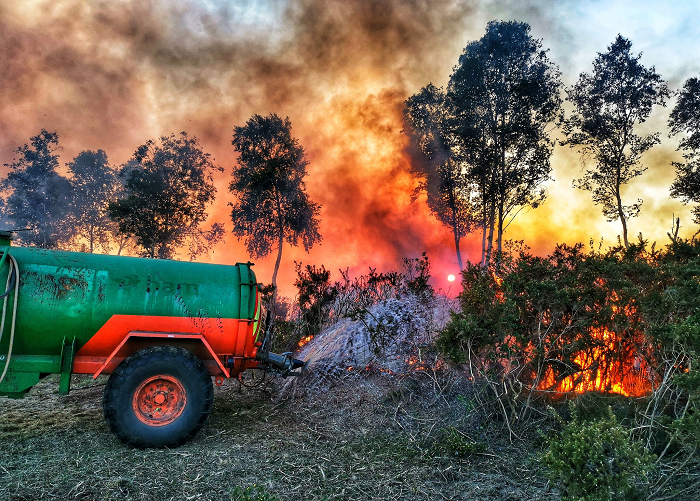 A tractor sprays water on to a grass fire on Thursley Common