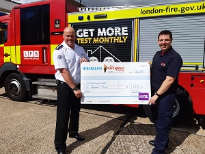 Firefighter Jimmy Durant handing over a cheque for £1000 to The Fire Fighters Charity.