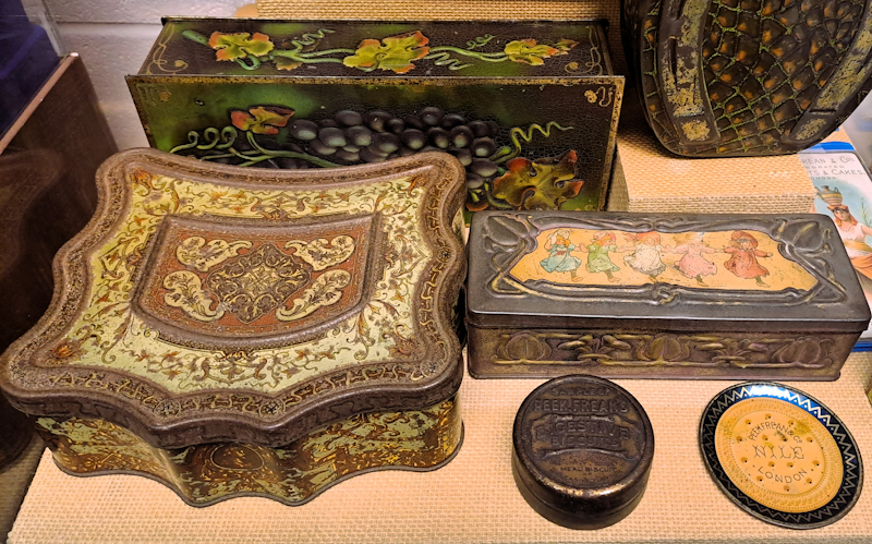 Close up of several examples of Peek Frean biscuit tins with colourful or embossed decorations. They are on display at the Peek Frean Museum, located at the former factory site in Bermondsey.