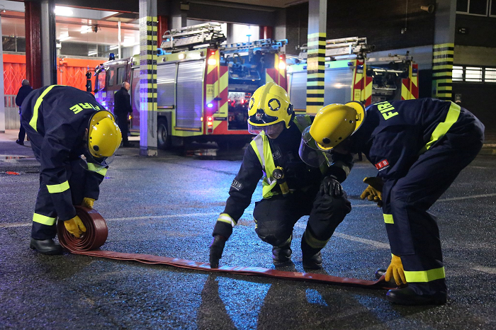 Three fire cadets carrying out a hose drill at a fire station.