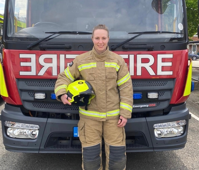 Jade Konkel wearing fire gear and standing in front of fire engine