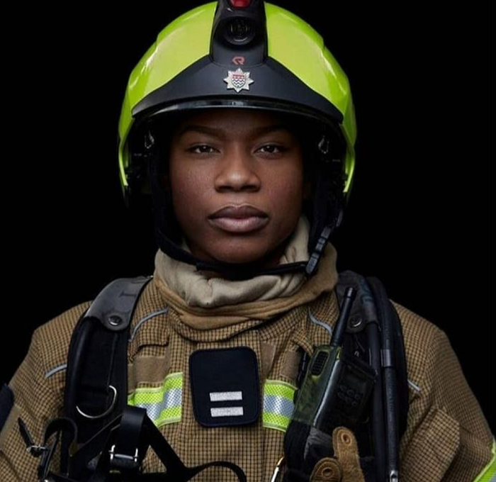 Kylei Holmes-Lewis wearing fire gear in front of a dark background