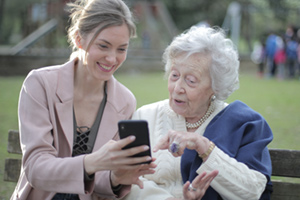 Two smiling women looking at something on a phone.