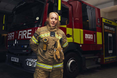 Firefighter standing in front of a fire engine.