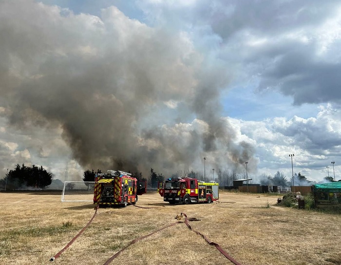 Fire engines on field with large smoke plume in background