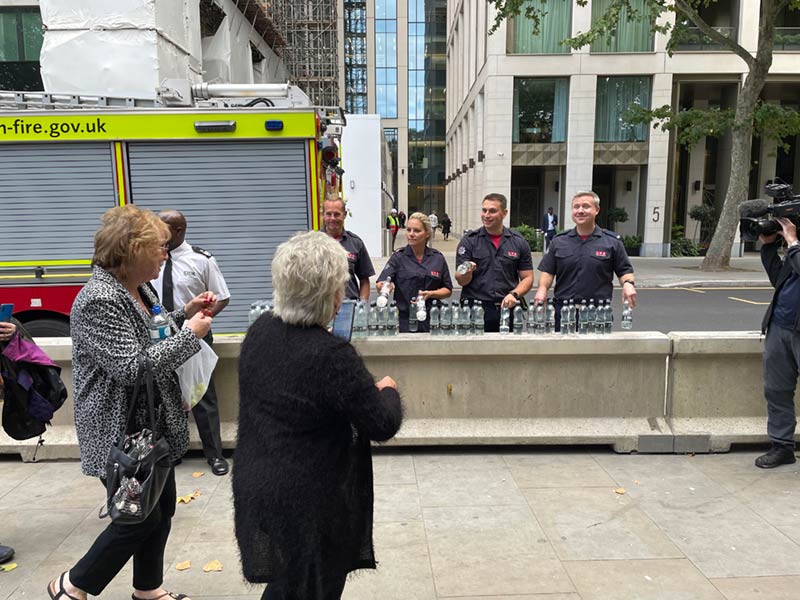 Firefighters handing out bottles of water to people in the queue.