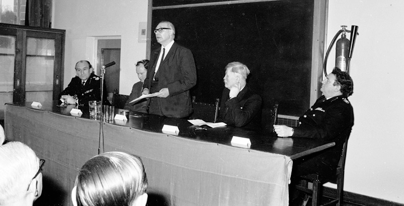 The Leader of the GLC (standing), Paddy Henry, Chairman of the GLC's Fire Brigades Committee (to his left) and Joe Milner, Chief Officer of LFB (far right) giving a press conference and presentation.