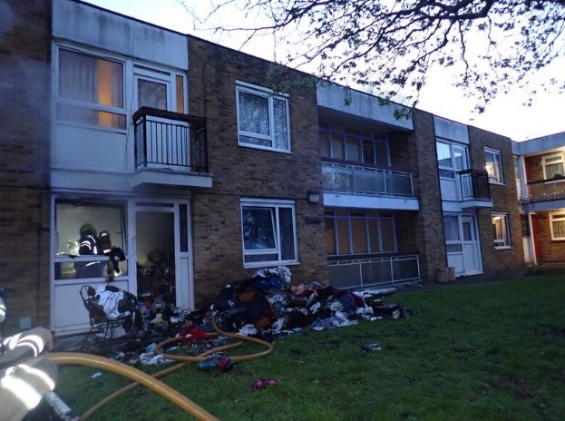 A block of flats with lots of possessions piled outside the window. 