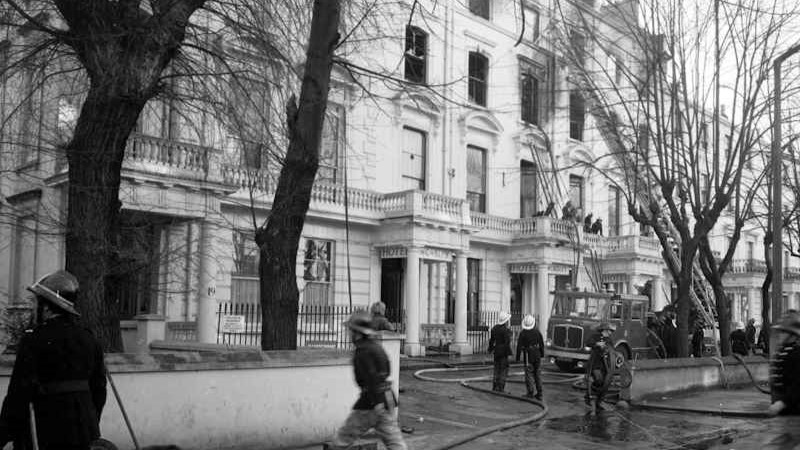 Exterior view of the Worsley Hotel in 1974 after the fire was put out. London Fire Brigade crews attended the scene and there are several firefighters, pieces of equipment and a fire engine in front of the building.