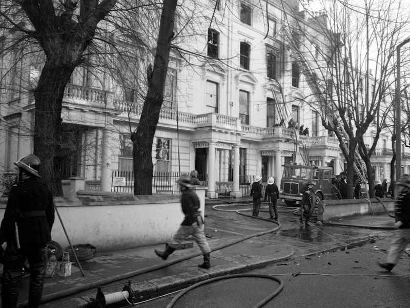 Exterior view of the Worsley Hotel in 1974 after the fire was put out. London Fire Brigade crews attended the scene and there are several firefighters, pieces of equipment and a fire engine in front of the building.