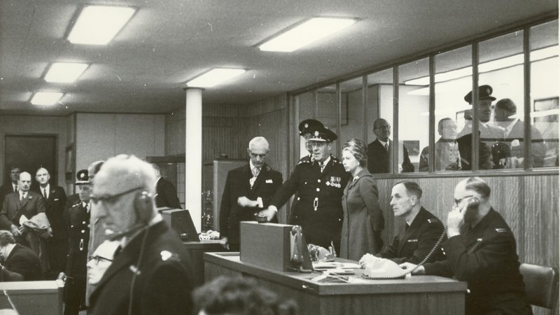 a black and white photo of Queen Elizabeth the Second, in the control room of 8 Albert Embankment